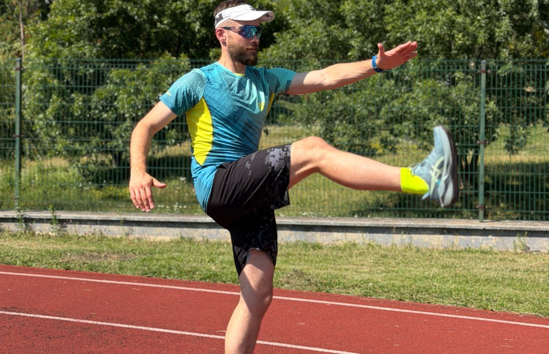 Biegacz w koszulce SMMASH na bieżni lekkoatletycznej